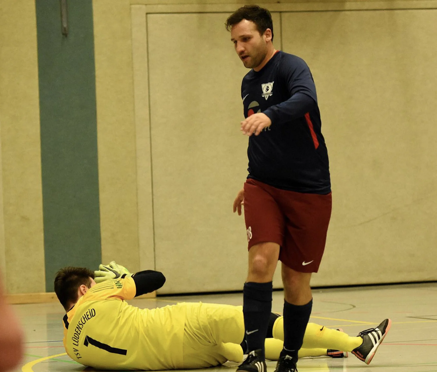 Fußballspieler stehend und ein Torwart auf dem Boden